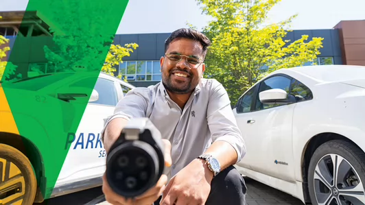 person holding a charging cable beside an electric car