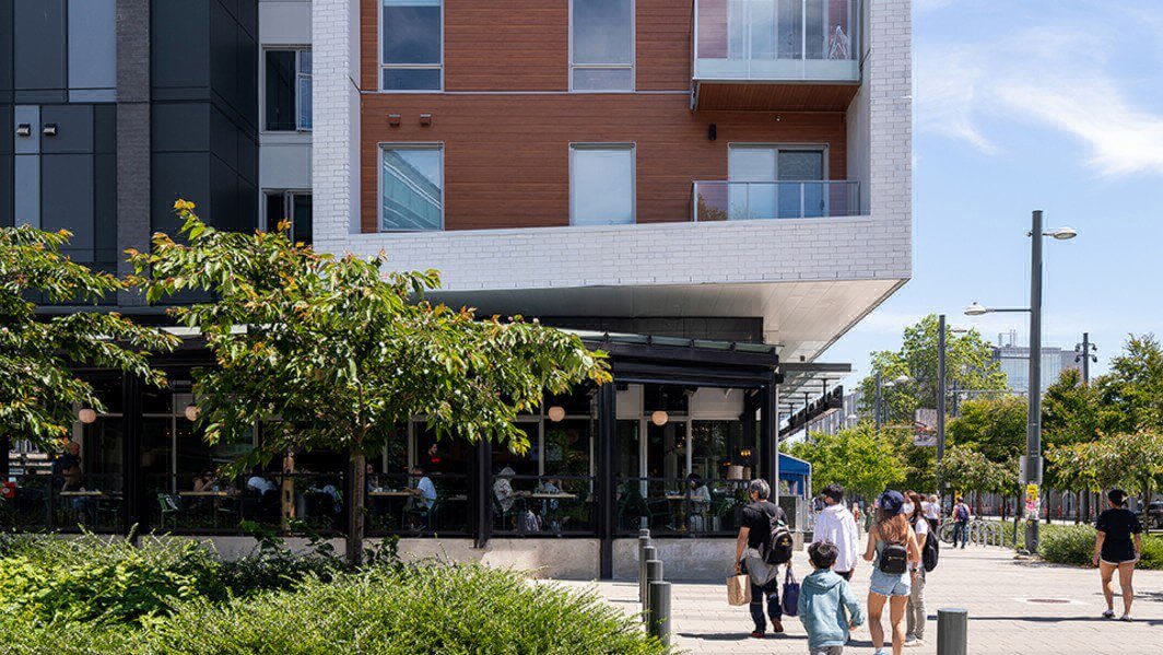 Outdoor shot of building with people walking and dining inside.