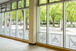 View of campus through windows with Indigenous art panels in the foreground