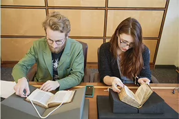 Two students looking at books sitting at a table in the Special Collections Reading Room
