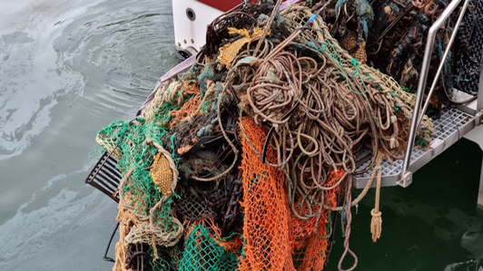 Image of abandoned fishing gear being picked by a boat at the ocean