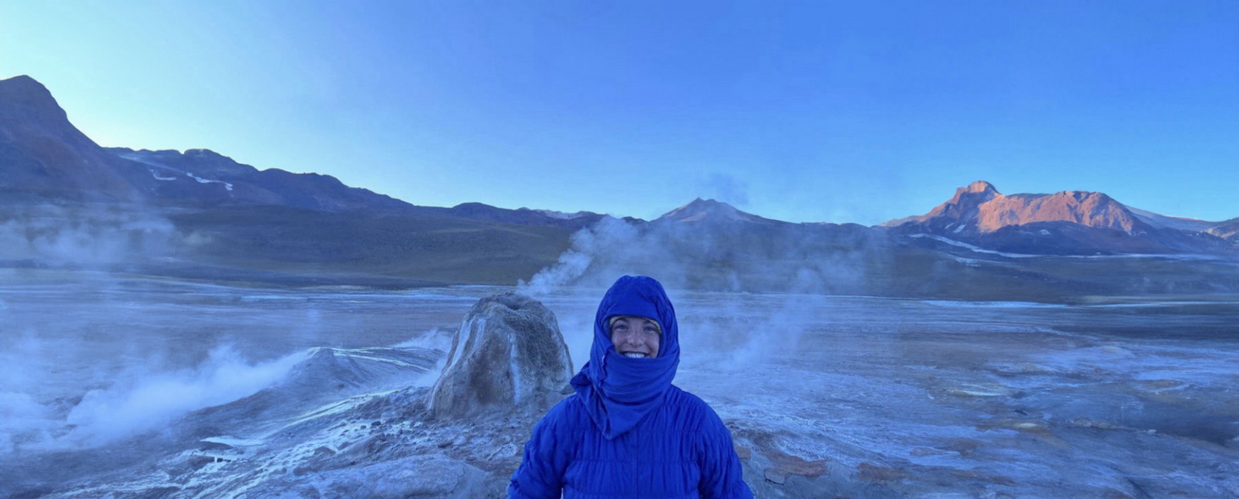 Haley Hood in a blue jacket standing in front of a mountain