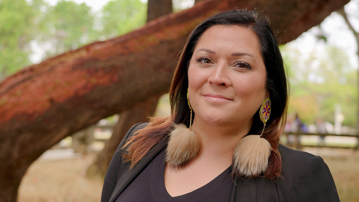 Dr. Heather Iglioliorte faces the camera and stands in front of an arbutus tree.