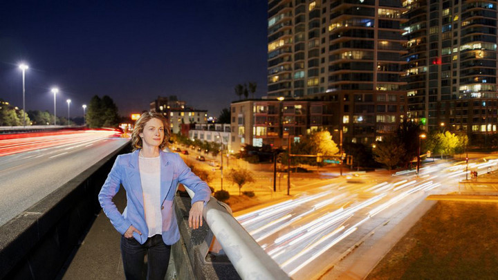 McPherson standing on a Vancouver city bridge at night with roads and buildings in background.