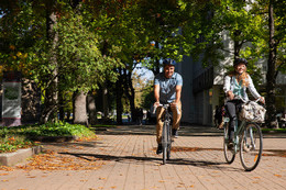 Two people cycling on campus.