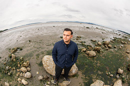 UVic graduate fellow Andrew Ambers stands on the shore of Cordova Bay while the tide is out.