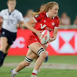 UVic women's rugby player Carissa Norsten runs down the field carrying a rugby ball.