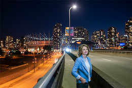 UVic researcher Madeleine McPherson stands on a Vancouver bridge at night surrounded by city lights.