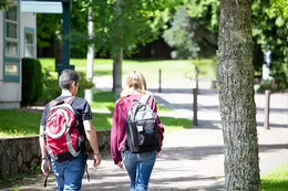 Two students wearing backpacks walk on campus.