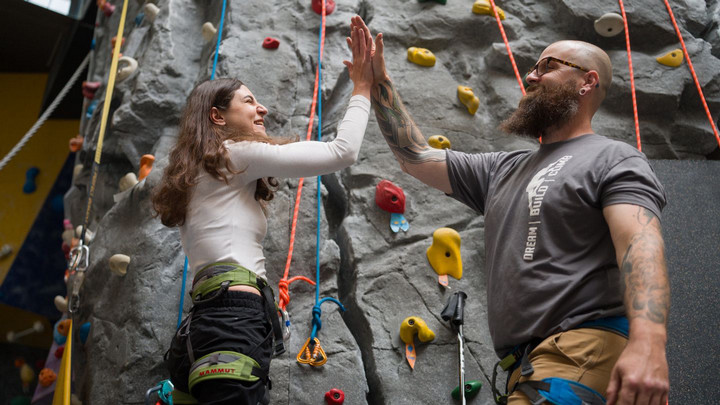 Two people hi-five in front of an indoor climbing wall