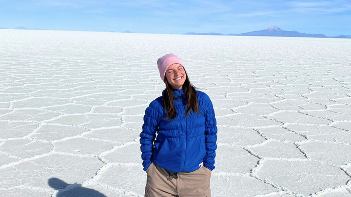 a woman in a blue jacket and a pink hat standing in the middle of a salt flat