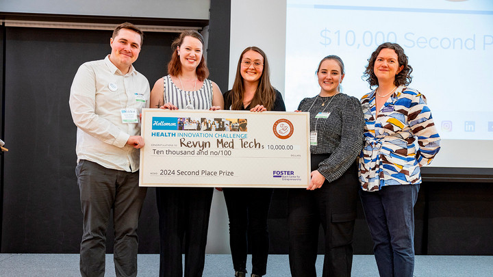 Four Revyn company members: Joshua Latimer, Devon Carmichael, Keeley McCormick, Samantha Sperling stand with Jessica Roberto – Assistant Director of the Holloman Health Innovation Challenge at the University of Washington who is presenting the group with a large cheque