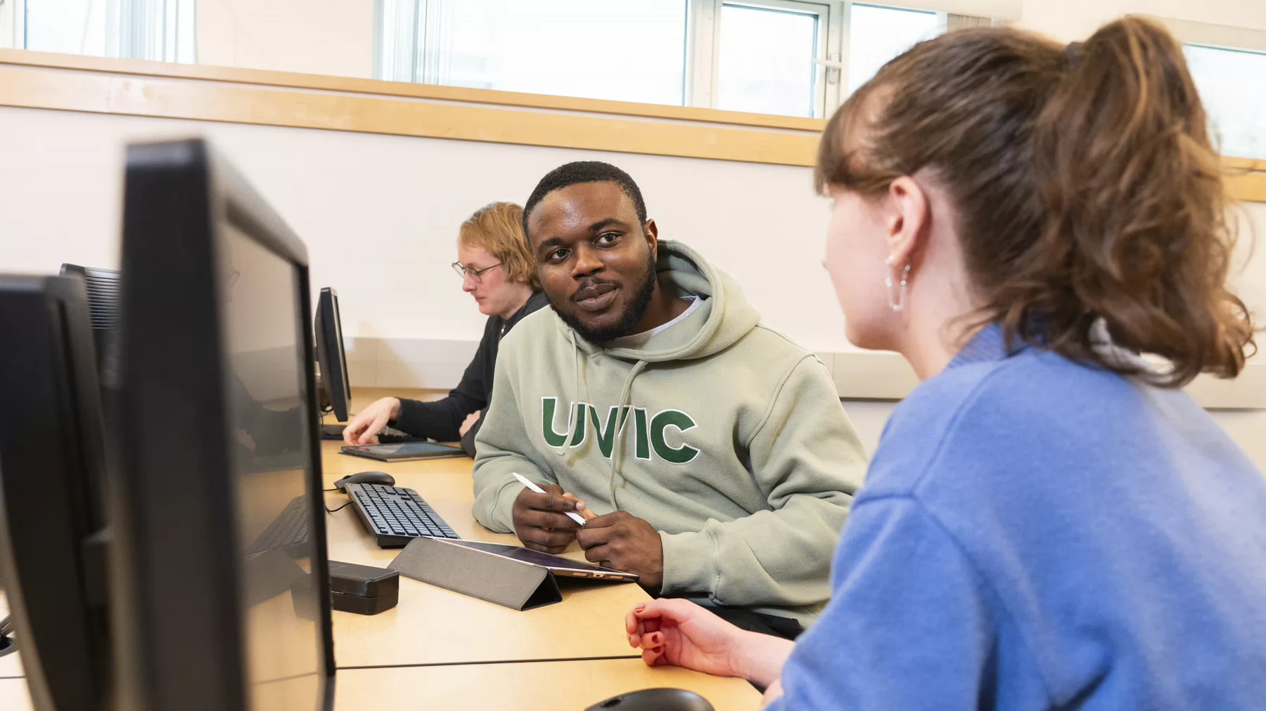 Three students work together on a computer.