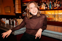 Woman smiling while leaning against a bar. 