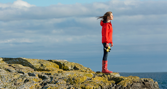 Female student standing on rocks near the ocean