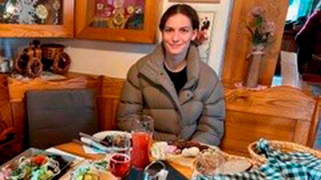 A student sits at a table in front of a meal.