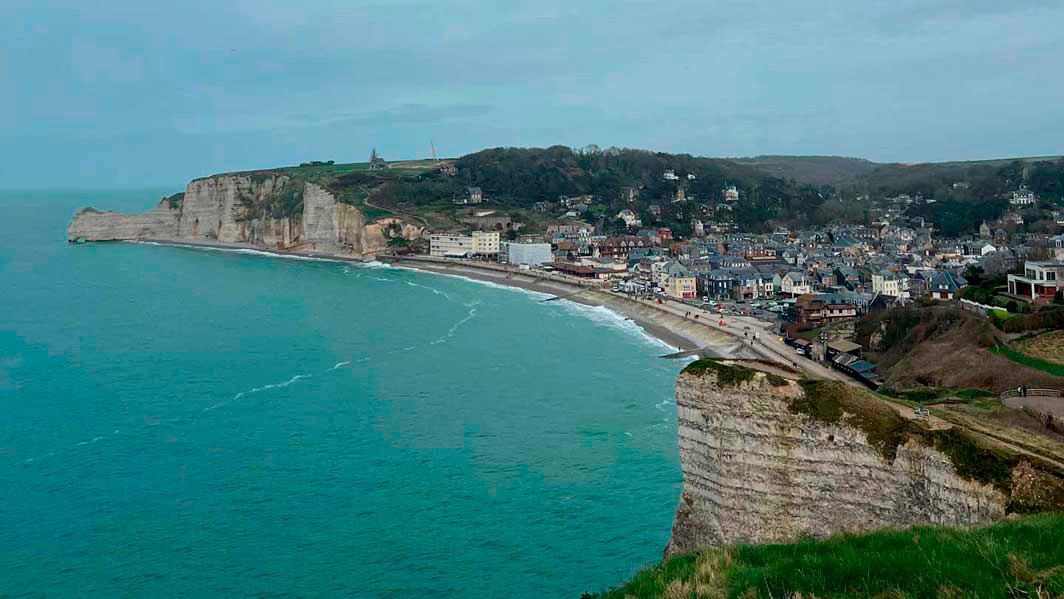 A photo of a shoreline with some buildings and a cliff.