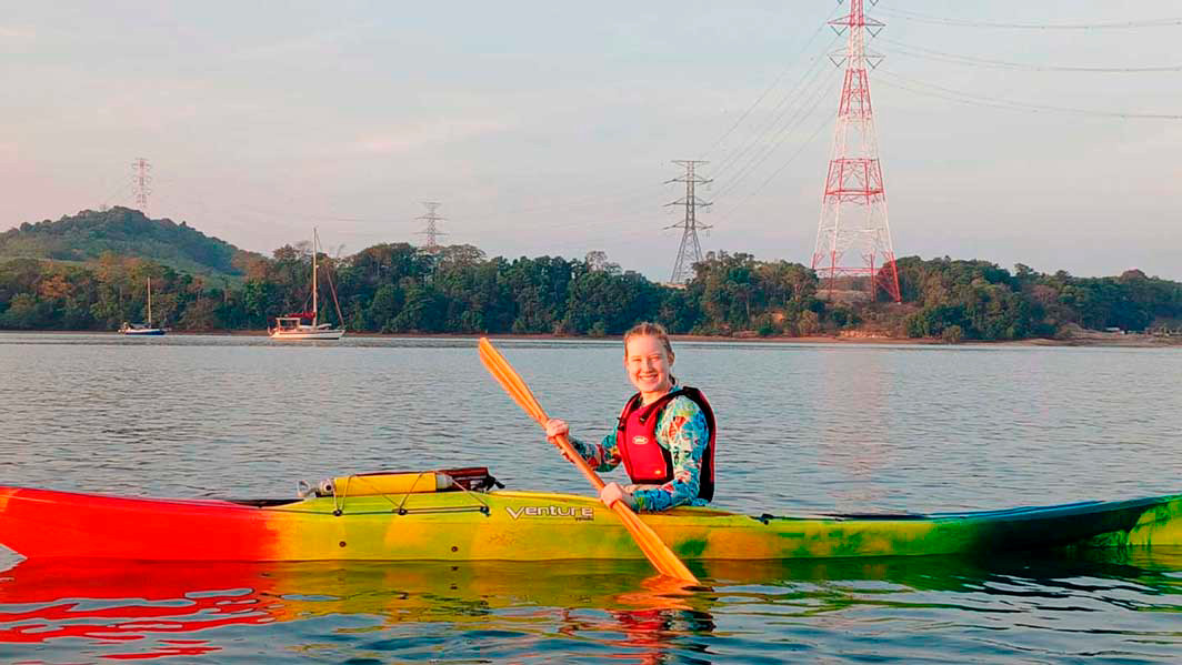 A student sits in a kayak on a body of water.