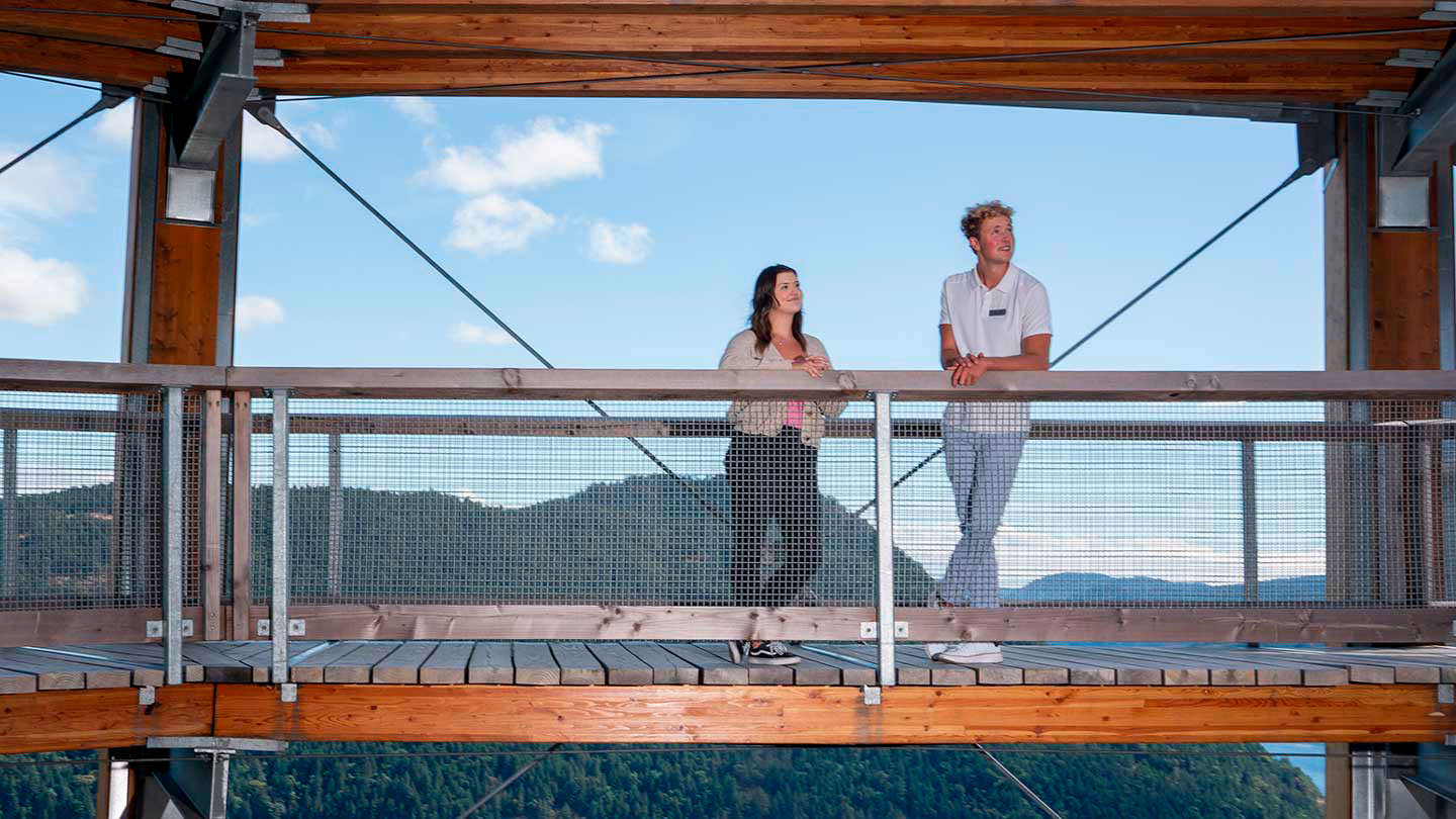 A student and his employer stand on top of the Malahat Skywalk with mountains and sea behind them.