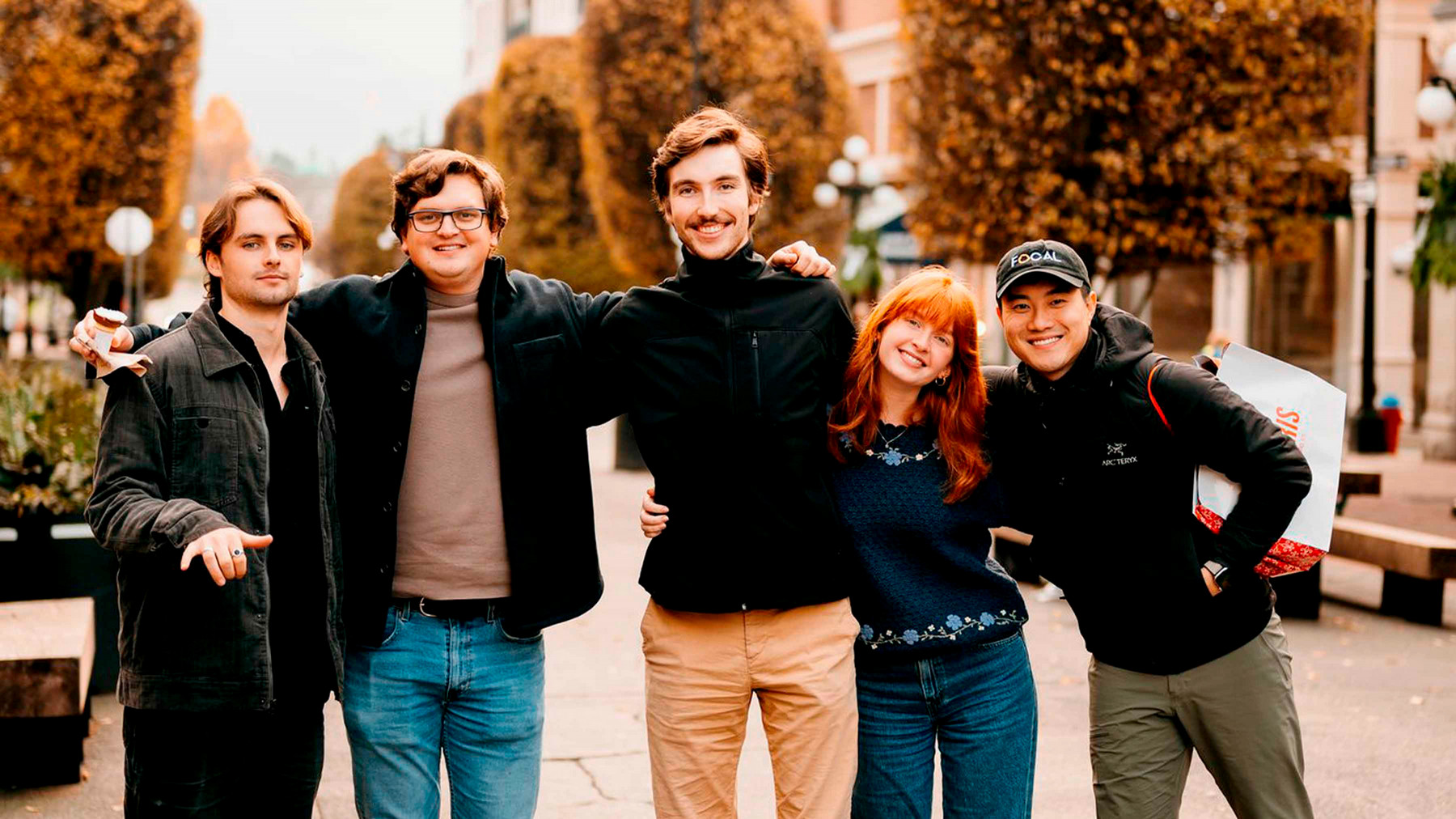 A group of people stand together smiling in the street.