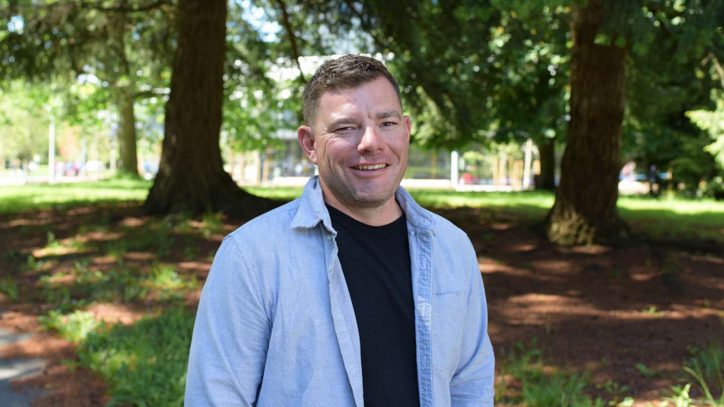 A portrait of Tahohtharatye Joe Brant on the UVic campus in Spring 2024. 