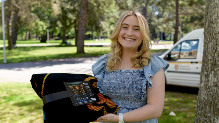 Victoria Jackson is pictured outside on campus holding her award envelope and a folded blanket.