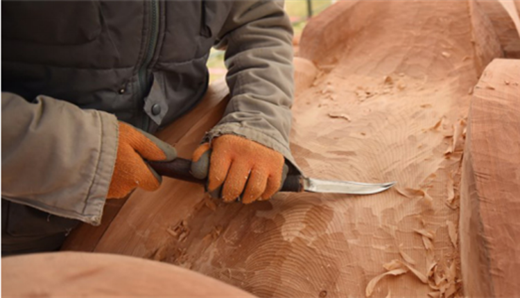 An indigenous community member carving a large tree trunk.