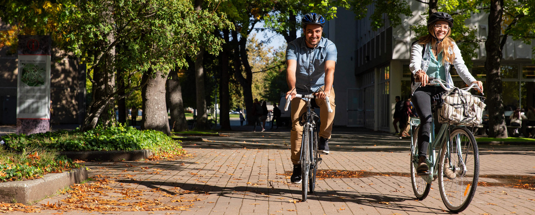 Two people cycling on campus.