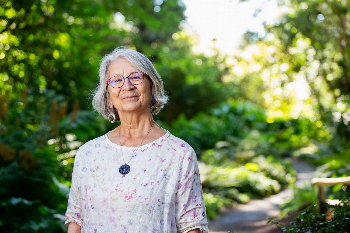 Val Napoleon stands in a green space on UVic campus