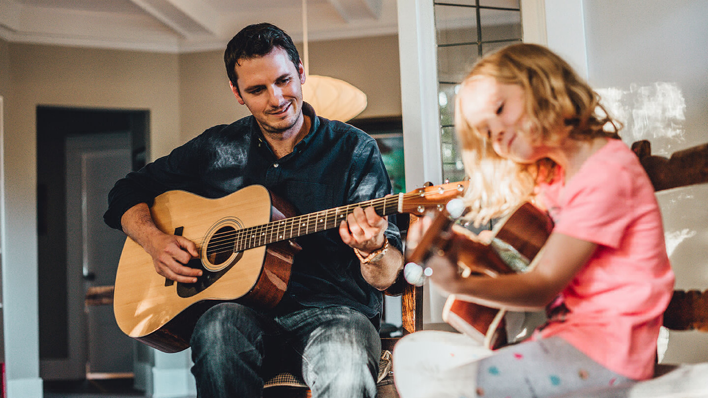 Jesse Horwood teaches a young child how to play guitar