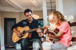 Jesse Horwood teaches a young child how to play guitar