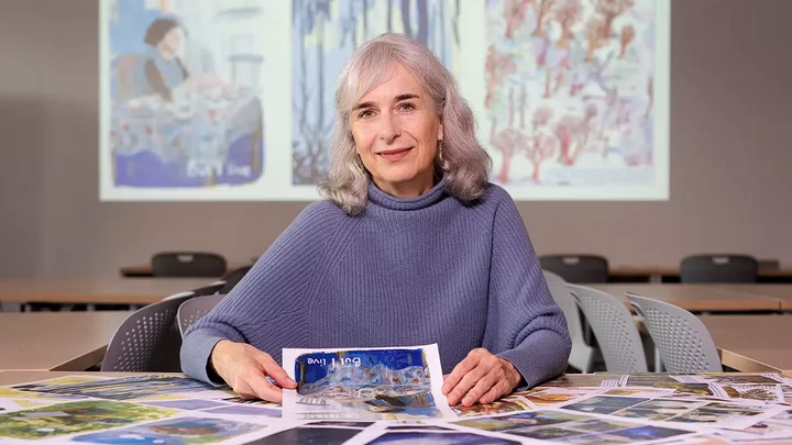 Charlotte sitting at a table with pages from a soon-to-be-published graphic novel.