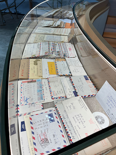 A large collection of letters and envelopes arranged in a glass display case