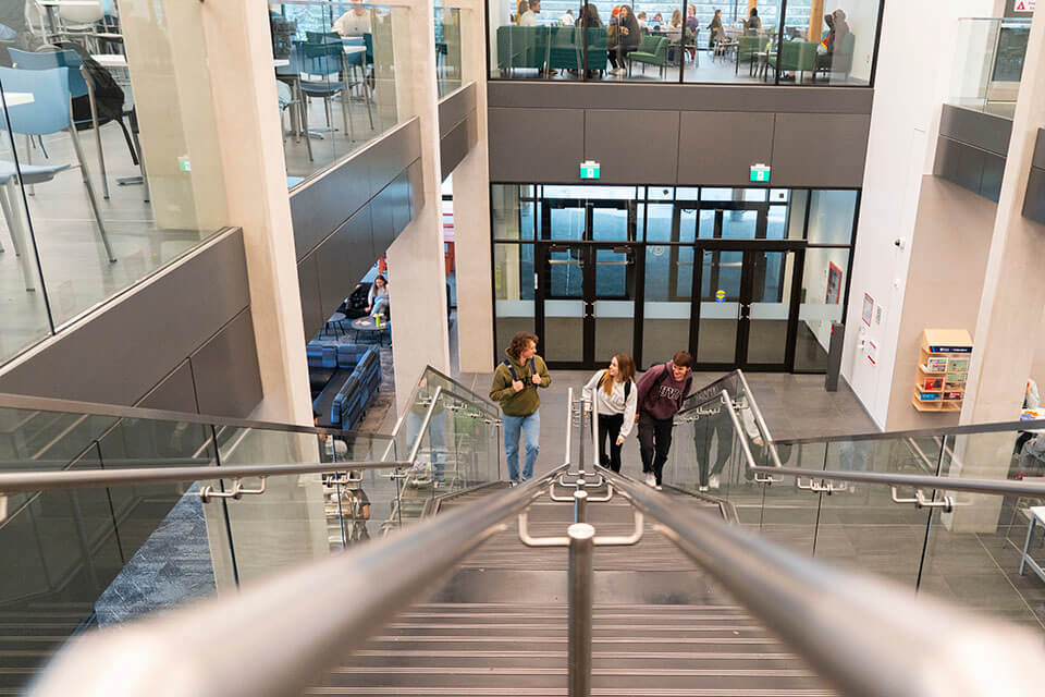 Three students walk up the stairs in the Cove