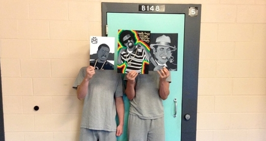 Participants in the Youth in Custody project hold art in front of their faces. 