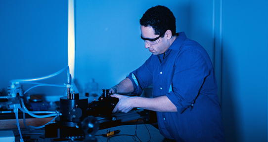 Chemistry graduate student Sun Kly in a lab with blue lighting