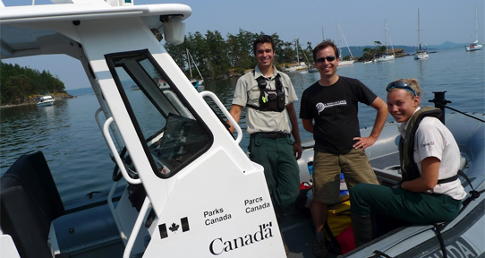 Three people on a Parks Canada boat