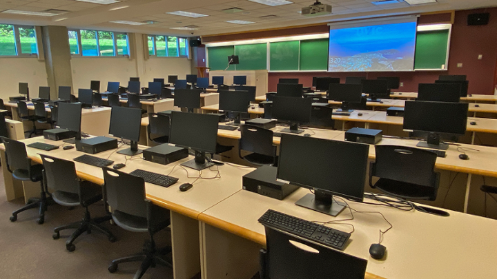 A classroom with rows of computer desks facing instructor station.